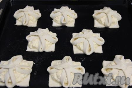 Соединить противоположные уголки квадрата из слоёного теста над начинкой, скрепить тесто пальцами по середине, получится очень симпатичный цветочек из слоёного теста. Таким же образом сформировать "цветочки" из всех квадратов с разрезами.