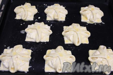 Яичный желток взбить в небольшой ёмкости. Смазать тесто взбитым желтком и поставить противень со слойками с творогом и лимоном в разогретую духовку, выпекать минут 25 (до золотистости) при температуре 200 градусов.