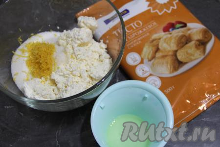 Подготовить продукты для приготовления слоек с творогом и лимоном. Слоёное тесто я использовала бездрожжевое, можно взять дрожжевое - это дело вкуса. Тесто разморозить при комнатной температуре. Лимон хорошо вымыть. Снять с лимона цедру, не затрагивая находящийся под ней белый слой, нам потребуется 1 чайная ложка цедры. Выдавить из лимона сок, нам понадобится 2 чайных ложки сока.