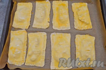 Отложенный ранее желток разбавить 2 столовыми ложками воды, перемешать и получившейся смесью смазать слойки сверху.