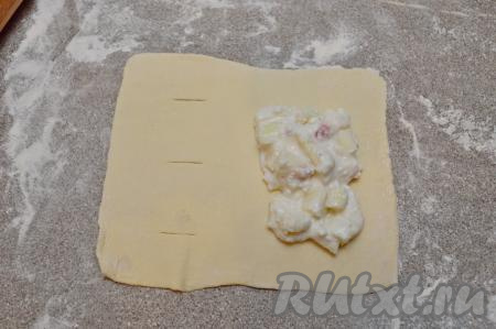 В центр второй стороны прямоугольника (то есть стороны, на которой нет надрезов) выложить 1,5 столовых ложки начинки из творога и персика. 
