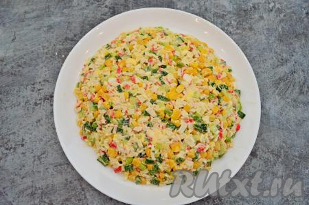 На плоское блюдо, подходящее по размеру, выложите небольшой горкой крабовый салат. Как следует прижмите салат лопаткой и хорошо выровняйте, чтобы крабовый салат напоминал полусферу и был достаточно плоским сверху (на достаточно плоскую поверхность в дальнейшем будет удобнее выкладывать рисунок в виде дракона).