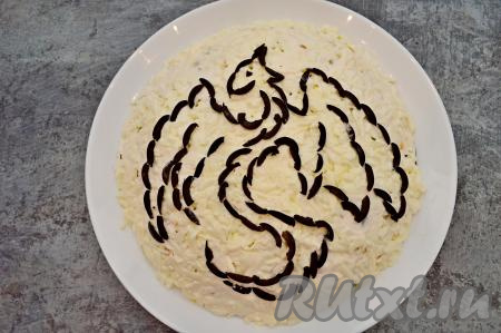 Маслины без косточек нарежьте на тонкие полоски. Выложите из кусочков маслин аккуратно фигурку дракона. Если делать всё аккуратно, то много времени это не займёт.