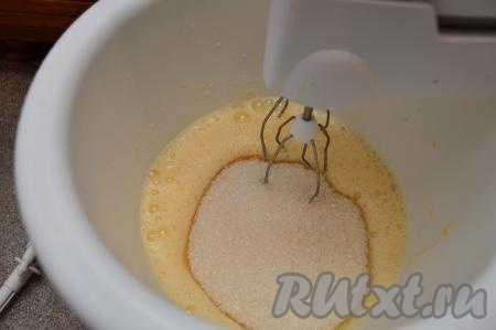 В ёмкость, удобную для взбивания миксером, вбить сырые яйца. Миксером взбить яйца в течение минуты на максимальной скорости, затем всыпать сахар. Взбивать яйца с сахаром на максимальной скорости в течение 5 минут.