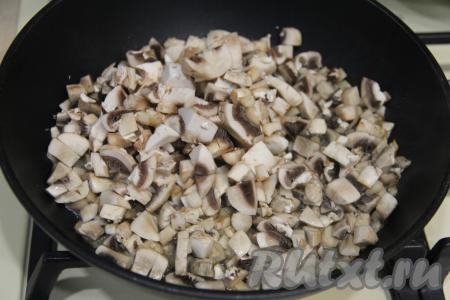 К обжаренному луку выложить шампиньоны, нарезанные достаточно мелко, перемешать.