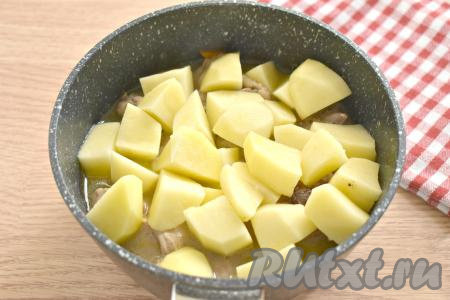 Через 10 минут к протушившимся кусочкам курицы добавляем очищенную и крупно нарезанную картошку.