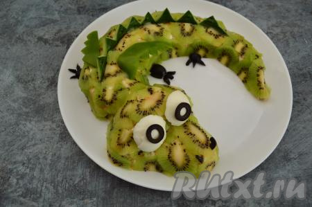 Вырезать из маслин кружочки. Из отложенных белков яиц и кружочков из маслин сформировать глаза, расположить их на мордочке дракона. Из болгарского перца вырезать  крылышки дракончика. Лапы и ноздри сделать из маслин. Дать салату обязательно пропитаться в холодильнике, как минимум в течение 30 минут, и можно подавать к столу.