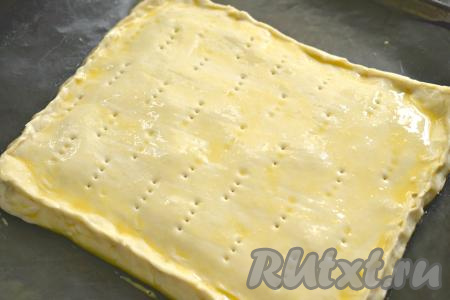 Второй пласт теста тоже немного раскатываем, закрываем им начинку, скрепляем края пирога. По всей поверхности пирога вилкой делаем проколы (проколы нужны для того, чтобы тесто не вздувалось во время выпечки). Слегка взбиваем яйцо венчиком (или вилкой). Смазываем поверхности слоёного пирога яичной смесью.