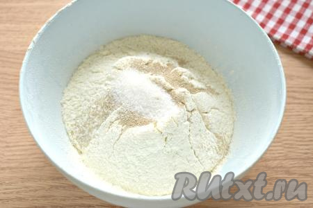 Прежде всего замесим дрожжевое тесто для пиццы, для этого просеиваем в широкую миску пшеничную муку, сразу же всыпаем сахар, соль и сухие быстродействующие дрожжи, очень хорошо перемешиваем, образуя в центре воронку.