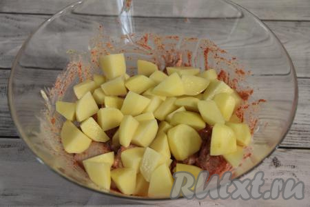 Добавить картошку в миску с куриными крылышками, покрытыми майонезом со специями.