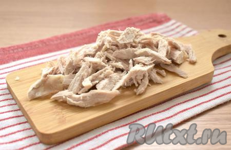 Нарезаем варёное куриное мясо на маленькие брусочки или разбираем на волокна.
