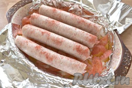 Сверху на овощи выкладываем купаты. Я приправила купаты молотой паприкой, вы можете использовать свои любимые специи и приправы.