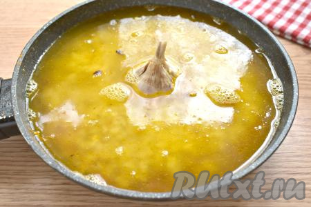 Содержимое сковороды заливаем кипячёной водой. Небольшую головку чеснока тщательно моем, очищать её не нужно. В центр сковороды ставим целую головку чеснока.