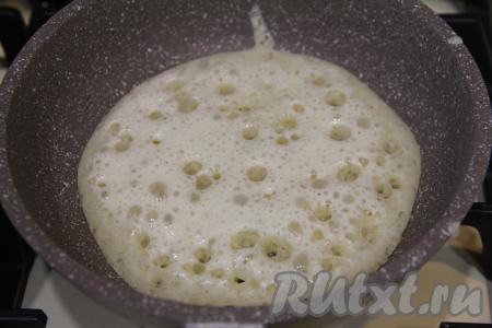 Сковороду (я взяла сковороду диаметром 18 сантиметров) немного смазать растительным маслом, очень хорошо разогреть, огонь уменьшить до среднего. Влить в сковороду половник дрожжевого блинного теста, равномерно распределить его по дну сковородки. Когда блинчик покроется сверху дырочками, а снизу подрумянится, перевернуть его.