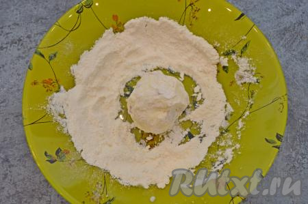 В глубокую тарелку насыпать муку. Я обычно из указанного количества ингредиентов формирую 8 сырников, поэтому визуально делю творожное тесто с курагой на 8 примерно равных частей. Влажными руками взять одну часть теста, сформировать круглый сырник и сразу обвалять его со всех сторон в муке.