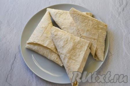 В результате получится треугольник из лаваша с творожно-яблочной начинкой. Формовка треугольником очень удобна - вся начинка остаётся внутри и при обжаривании не выпадает из лаваша. Сформируйте таким же способом треугольники с начинкой из оставшихся трёх полосок лаваша.