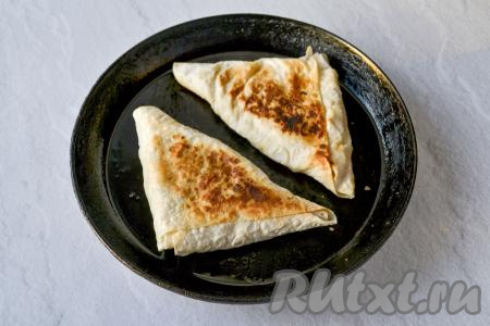 Затем переверните и обжаривайте под крышкой на минимальном огне до подрумянивания второй стороны. Обжаренные лаваши переложите на тарелку. Аналогично обжарьте оставшиеся два треугольника из лаваша с творогом и яблоками. При таком способе обжарки яблоки станут мягкими, как крем, лаваш поджарится, но не подгорит даже с минимальным количеством масла.