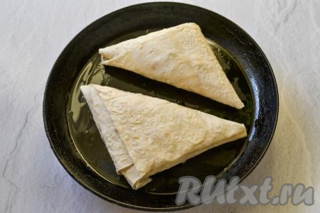Разогрейте сковороду с растительным (или сливочным маслом) и выложите на неё треугольники (у меня поместилось на сковороду 2 треугольника). Сделайте огонь минимальным и под крышкой обжаривайте лаваш с яблоками и творогом до румяной корочки с одной стороны в течение 6-8 минут (до подрумянивания снизу).