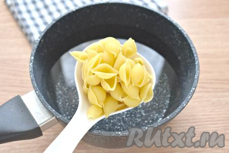 Прежде всего сварим макароны, для этого наливаем в кастрюлю воду, по вкусу её солим и на огне доводим до кипения. Как только вода закипит, выкладываем в неё макаронные изделия и сразу перемешиваем. С момента закипания варим макароны на небольшом огне до готовности (примерно 8-10 минут), периодически перемешивая, чтобы они не прилипли ко дну кастрюли. Разные сорта макарон варятся различное время, поэтому можете посмотреть точное время варки на упаковке макаронных изделий, которые вы готовите.