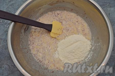 В миску всыпать половину муки. Лопаткой вмешать муку в тесто.