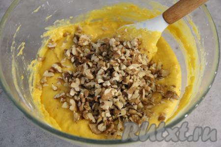 Частями добавить оставшуюся просеянную муку, каждый раз хорошо вмешивая её в тесто с помощью лопатки. Добавляя муку, учитывайте, что тесто для кекса должно получиться в меру густым, однородным. Грецкие орехи порубить ножом и добавить в тесто.