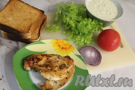 Обжаренную курочку остудить. Приготовить соус, для этого нужно маринованный огурец натереть на мелкой тёрке, отжать лишнюю влагу. Огуречную массу переложить в небольшую ёмкость, добавить пропущенный через пресс чеснок, сметану и майонез, перемешать получившийся соус. Помидор нарезать на тонкие кружочки. Сладкий красный лук нарезать на тонкие кольца.