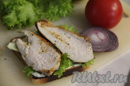 Куриное мясо разрезать на тонкие ломтики. Выложить половину нарезанного мяса на листья салата. 