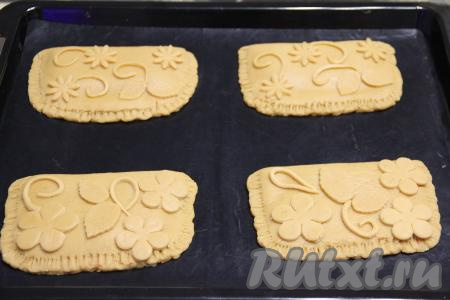 Оставленный кусочек теста для украшения тонко раскатать скалкой, а затем из раскатанного теста вырезать цветочки или украшения по желанию. Для этого можно воспользоваться вырубками для печенья или вырезать острым ножом произвольный рисунок. Выложить узоры из теста на поверхность пряников.