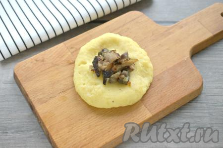 Плотное картофельное пюре делим примерно на 6 кусочков (весом около 100 грамм каждый). Формируем из каждого кусочка картофельную лепёшку диаметром примерно 8-9 сантиметров. В центр кладём столовую ложку с верхом грибной начинки.