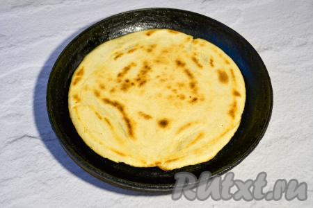 Затем переверните лепёшку и также обжаривайте вторую сторону (до золотистости). Готовую лепёшку переложите на тарелку. Аналогично пожарьте вторую лепёшку.