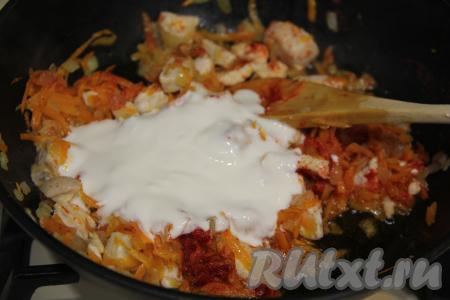 В сковороду с обжаренным куриным мясом добавить соль, специи, сметану и мелко нарезанный чеснок, перемешать.