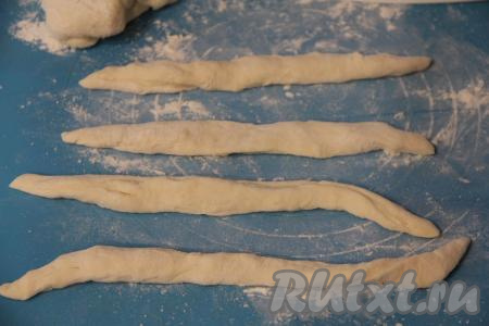 Пока обжаривается мясо курицы, приготовим галушки. Для этого в кастрюлю нужно влить воду, подсолить по вкусу и довести до кипения. "Отдохнувшее" тесто разделить на 4-6 частей. Из каждой части теста на присыпанной мукой поверхности сформировать длинный жгутик.