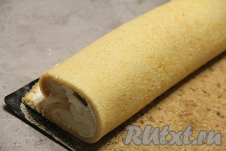 Завернуть корж с кремом и киви в плотный рулет, начиная со стороны, ближе к которому лежат киви, и помогая при сворачивании ковриком (или пергаментом), на котором выпекали бисквит.