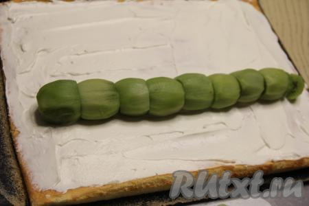 Выложить киви на корж с кремом, отступив 10 сантиметров от длинного края.