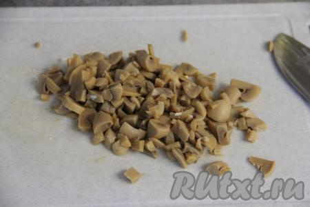 Маринованные шампиньоны откинуть на дуршлаг, дать стечь маринаду. Затем мелко нарезать грибы.