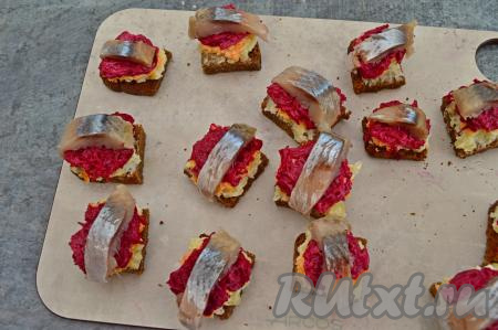 Филе селёдки осматриваем, удаляем, если есть, косточки. Нарезаем рыбу на кусочки. Выкладываем по кусочку рыбки сверху на каждый порционный бутерброд. Всего у меня получилось 12 канапе.