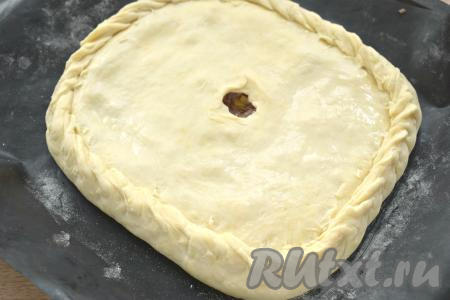 Раскатываем второй кусок теста, накрываем им начинку, скрепляем края курника, в центре пирога делаем отверстие для выхода пара. Поверхность пирога смазываем холодной водой.
