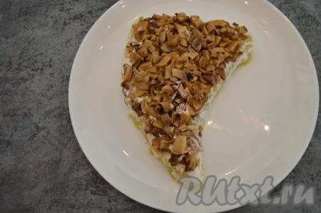 С маринованных грибов слить маринад. Мелко нарезать грибы и выложить ровным слоем поверх картофеля.