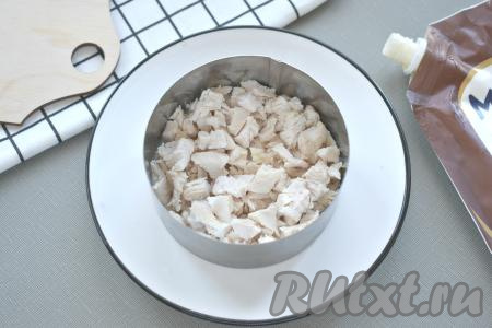 Заранее сварить куриное филе в подсоленной воде в течение 25-35 минут после закипания. Яйца отварить с момента закипания в течение 10 минут, морковку в кожуре - в течение 25-35 минут. Чернослив на 10 минут залить кипятком, затем воду слить, а сухофрукты обсушить на тканевом (или бумажном) полотенце. Варёные яйца, морковку и куриное мясо остудить. Когда все ингредиенты будут подготовлены, можно приступать к сборке салата "Прага". Я готовила его порционно, используя сервировочное кольцо диаметром 10 сантиметров (это 1 порция салата). Предложенного количества ингредиентов хватит на 3 порции салата, поэтому и ингредиенты равномерно распределяла на 3 порции. Можно выкладывать и в один достаточно глубокий салатник. На плоскую тарелку ставим сервировочное кольцо. Нарезаем мясо на мелкие кубики. Выкладываем в кольцо первым слоем часть мяса (поскольку я готовила 3 порции салата, соответственно и выкладывала в каждое кольцо 1/3 мяса), смазываем майонезом.