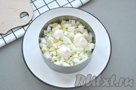 Очищенные яйца нарезаем достаточно мелко. Выкладываем 1/3 яиц следующим слоем салата, смазываем майонезом.