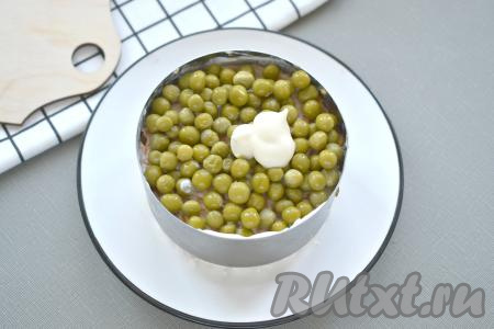  Горошек сначала откидываем на сито, чтобы слить с него лишнюю жидкость. Поверх морковки выкладываем 1/3 горошка, немного смазываем майонезом. 