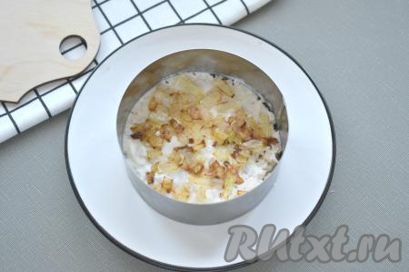 Нарезаем мелко очищенный лук и обжариваем его на сковороде на растительном масле до золотистости (в течение 3-4 минут) на среднем огне, иногда помешивая. Даём луку остыть, выкладываем 1/3 лука на слой из курицы.