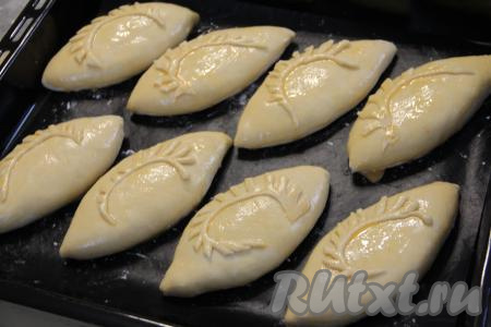 Яичный желток слегка взбить вилкой в небольшой ёмкости, а затем смазать верх пирожков желтком.