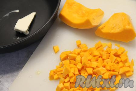 Пока тесто подходит, приготовим начинку. Для этого 300 грамм тыквы, очищенной от семян, волокон и кожуры, нужно нарезать на кубики размером, примерно, 1 сантиметр на 1 сантиметр. В сковороду выложить сливочное масло, поставить на огонь.