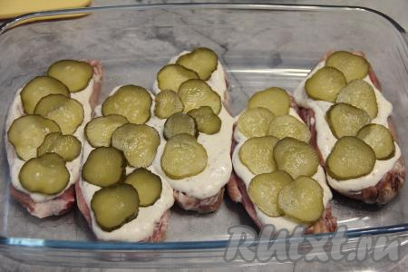 Солёные огурцы нарезать на тонкие кружочки и выложить поверх свинины.