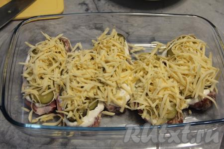 Поверх свинины с огурцами выложить натёртый на крупной тёрке сыр.