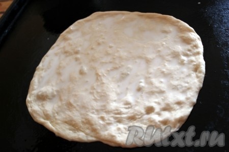 Разделите тесто на 4 части и раскатайте каждую в тонкую лепешку. Смажьте поверхность теста молоком и выложите на противень.