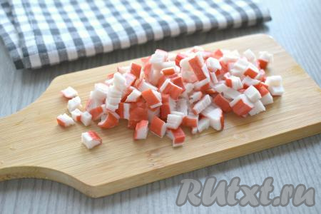Достаём из упаковки крабовые палочки, нарезаем их на маленькие кубики.