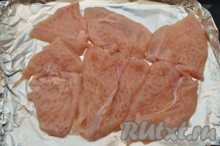 Противень для запекания застелить фольгой. На фольгу выложить куриные отбивные. Старайтесь выкладывать кусочки отбитого филе вплотную к друг другу, но без нахлёста.