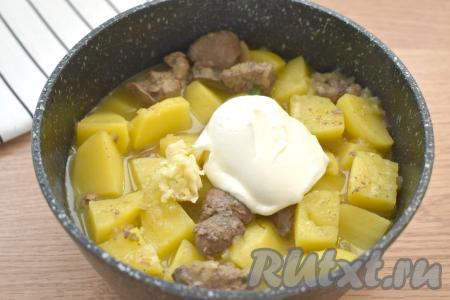 После того как картошка станет мягкой, добавляем сметану и мелко нарезанный чеснок. Аккуратно перемешиваем, даём закипеть и тушим картофель с куриной печенью на небольшом огне 5 минут.